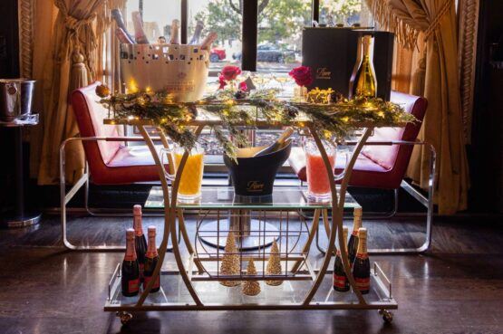 a bar cart with drinks on it in front of a window